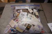 Photo of large resealable bag filled with many postage stamps from various countries, showing a wide variety of colors and designs.