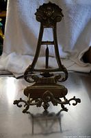 Front view of large brass easel showing full height, ornamental top and detailed base.