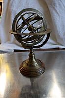 Front view of brass armillary sphere on wooden base, showing multiple brass rings and central sphere.