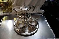 Photo of entire silverplate tea set arranged on serving tray including teapot, creamer, and sugar bowl.