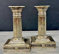 Pair of antique silver plated candlestick holders shown from front angle to display design and condition.