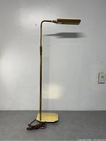 Full view of the antique polished brass adjustable floor lamp showing the lamp extended upright with rectangular lighting head.