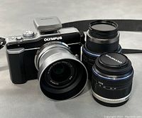 Olympus PEN E-PL1 camera body with two attached lenses displayed with lens caps
