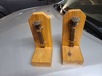 Front view of the pair of railroad spike bookends on a vehicle hood, showing the mounted spikes and wooden bases