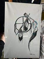 Full view of acrylic painting on canvas featuring indigenous symbols with feathers and arrow/staff, predominantly black with colorful accents on white background.