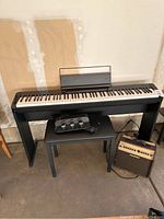 Full view of digital piano on stand with bench, pedal unit and amplifier