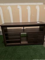 Front view of wooden entertainment center showing multiple storage compartments and drawers.