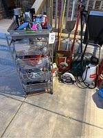 Overall lot view showing mesh cart, circular saw, hand tools, sprayer, and dolly