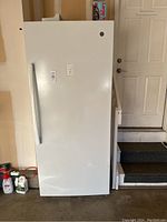 Full exterior view of the white upright freezer in a garage setting