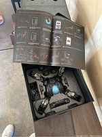 Mekamon robot inside foam packaging with instruction manual open showing setup and power down instructions.