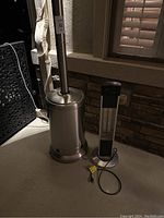 Both heaters side by side on an outdoor patio floor. Propane heater on left, electric heater on right.