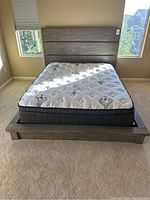 Front view of grey wooden platform bed frame with mattress in headboard, base, and slats visible