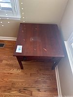Top view of the square wooden side table showing surface wear and scratches.