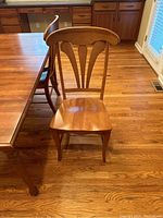 Close-up view of one wooden dining chair showing carved back and solid seat
