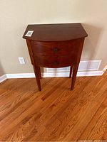 Front view of tall wooden side table showing two drawers and square metal knobs.