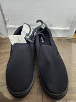 Front view of the men's black canvas slip-on shoes with size tag 13 visible and brand label Carter's attached.