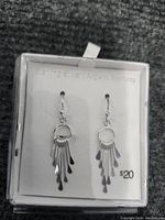 Photo showing front view of the pair of sterling silver dangle earrings hanging from a small hoop with elongated teardrop shapes, displayed on a white backing card labeled Argent Sterling