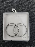 Sterling silver textured hoop earrings displayed in clear packaging.