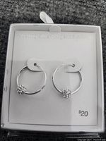 Pair of sterling silver hoop earrings on white display card with text 'Sterling Silver / Argent 925' and price $20 visible.