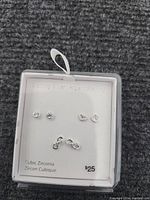 Photo of three pairs of sterling silver earrings with cubic zirconia and heart designs on white display card