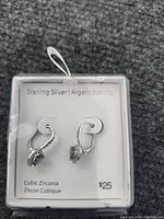 New pair of sterling silver earrings with cubic zirconia on a display card showing $25 price, with lever-back closure and loop design.