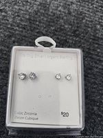 Photo of two pairs of sterling silver cubic zirconia stud earrings on a white display card, showing both sizes of stones and packaging details.