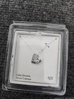 Sterling silver necklace with heart-shaped pendant of cubic zirconia on a chain, displayed in its original plastic box with price tag showing $25.