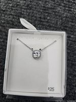 Sterling silver necklace with square clear stone pendant displayed in white box with $25 price tag.
