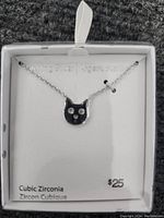 Photo of sterling silver cat necklace with cubic zirconia eyes on pendant displayed on white backing card.