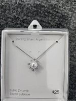 Photo of sterling silver necklace with pendant featuring central pearl and cubic zirconia stones on a display card.