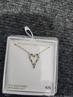 Photo of the gold plated sterling silver heart-shaped pendant necklace adorned with multi-colored gemstones, displayed on white jewelry packaging.