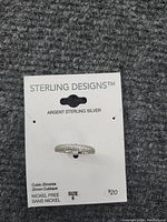 Ring attached to a Sterling Designs branded card stating it is argent sterling silver, nickel free, size 6, priced at $20.