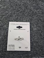 Photo of the sterling silver ring attached to a card labeled 'Sterling Designs' showing it is size 7 and cubic zirconia stones. Card also states nickel free.