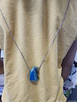 Full view of the necklace on a beige cloth background showing the chain and the pendant hanging at the center.