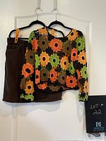 Photo showing the crochet top and brown corduroy skirt hanging on a door