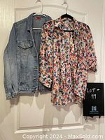 Blue denim jacket and floral blouse hanging on white door