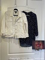 Both white denim jacket and navy blue polka dot top hanging on hangers
