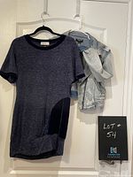 Blue sheath dress with black velvet trim detail hanging beside denim jacket on a door.