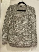 Front view of grey knit pullover sweater hanging on hanger showing overall condition, crew neckline, and pockets