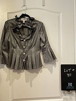 Front view of the metallic silver Josef Ribcoff jacket with ruffled collar, pleated detailing, and jeweled buttons.