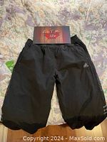 Front view of black Adidas men's snow pants laid flat showing elastic waistband and Adidas logo on left thigh.