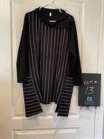 Front view of black pin striped tunic hanging on a hanger on a door, clear view of design and pockets