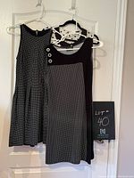 Three hanging polka dot clothing items visible front and back with different dot sizes and black panel accents.