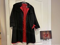 Photo showing trench coat hanging open, navy blue outside and candy apple red lining visible inside.