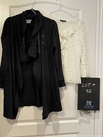 Black car coat and white lace top by YS Shine side by side on hangers, showing full items front view.