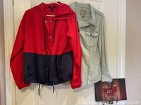 Red and navy blue shell jacket with hood by Forever 21 hanging next to the Guess blue jean look shirt on a door.