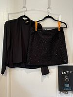 Photo of black long-sleeve blouse from Forever 21 and black embellished mini skirt from Mexx on hangers against a white door