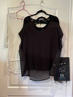 Photo showing three women's tops on hangers: black sheer U2B top with lace, black short-sleeve top with lace on shoulders, and white long-sleeve lace-detail top.