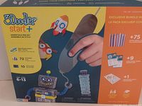 Box of 3Doodler Start+ essentials pen set showing contents including filament strands, activity guides, and stencil cards.