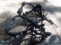 Black sport rack bike carrier lying on pavement with foam padding and adjustable straps visible.